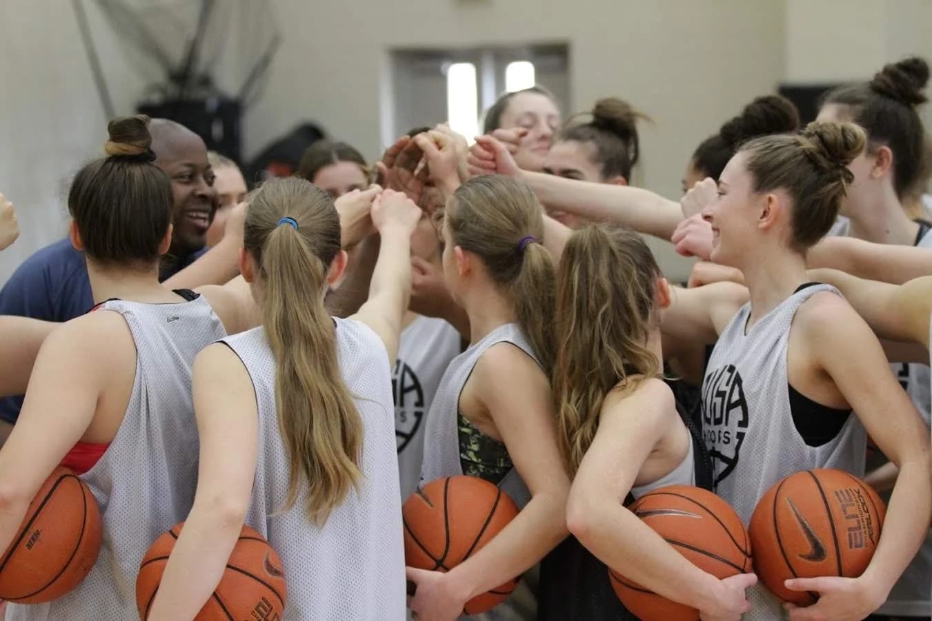 AUSA Hoops girls team huddled together, hands in, mid-celebration