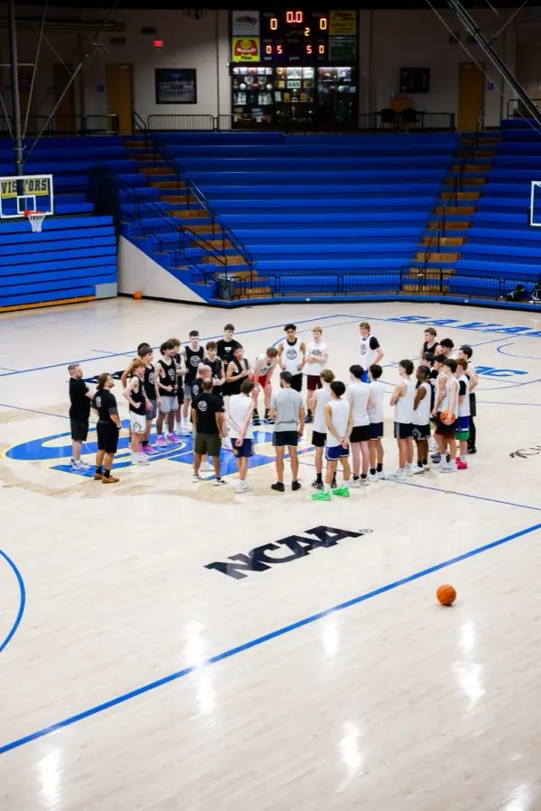 AUSA Hoops squad huddled at centre court in an NCAA college gym