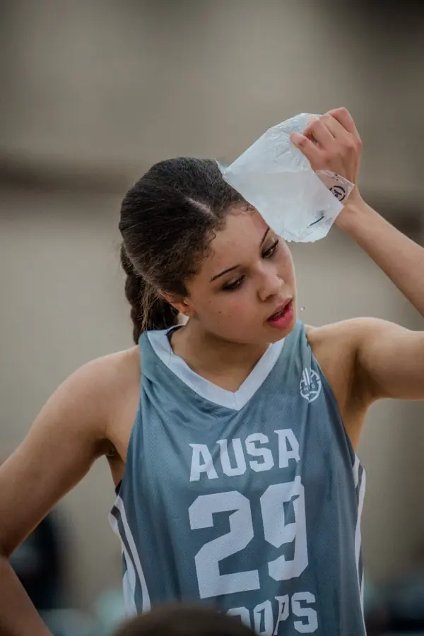 AUSA Hoops player holding an ice pack to her head courtside