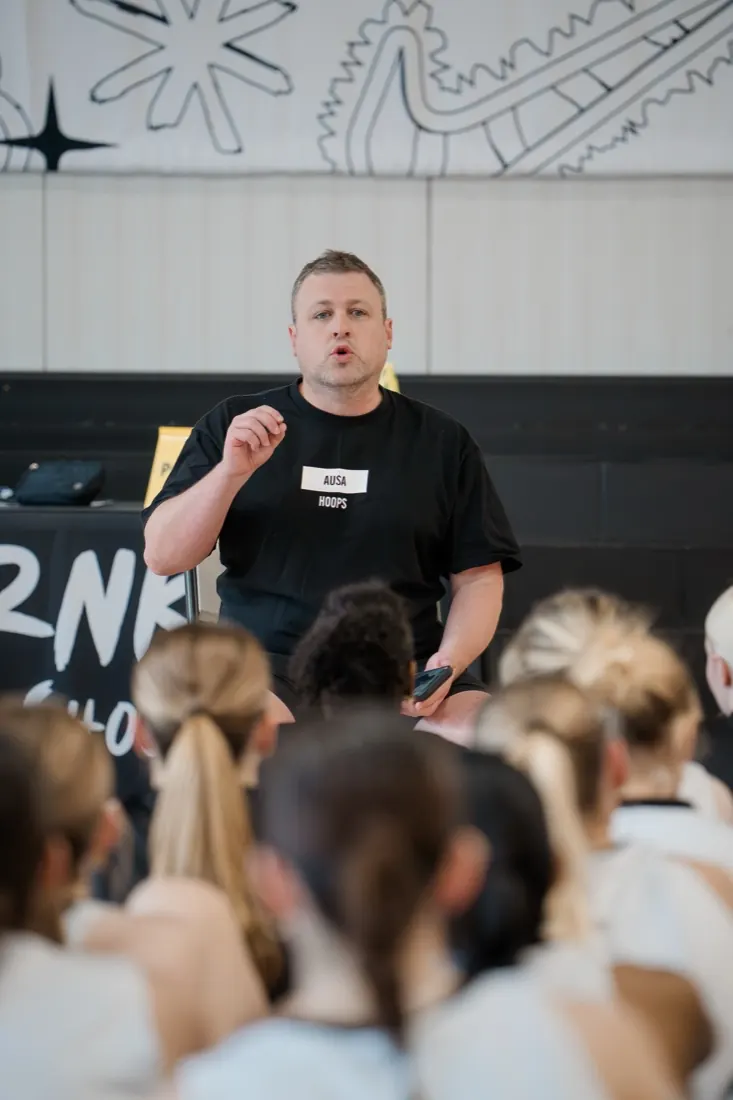 AUSA Hoops staff member briefing a squad of seated players at a US tournament